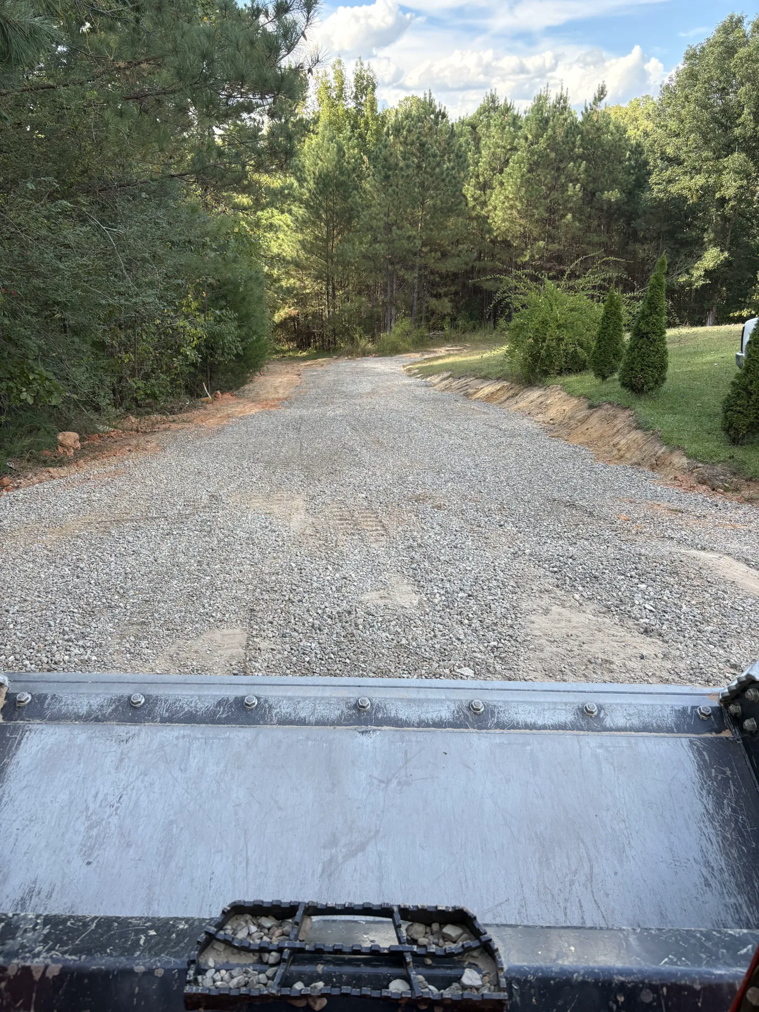 Gravel driveway after grading with drainage channel visible along the right side