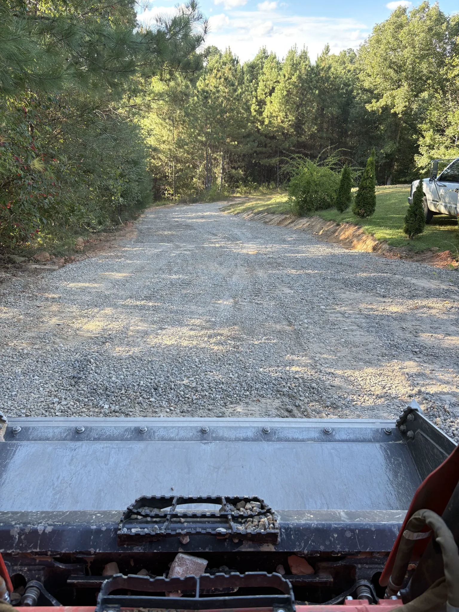 Fresh gravel covering the improved driveway after drainage and grading work